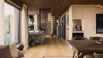 A modern kitchen with built-in appliances, a dining area with a wooden table, and a cozy seating area with a sofa and plants.