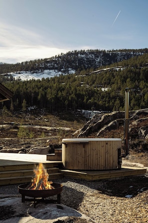 A wooden deck with a fire pit, a small wooden structure, and a view of a snowy mountain range.