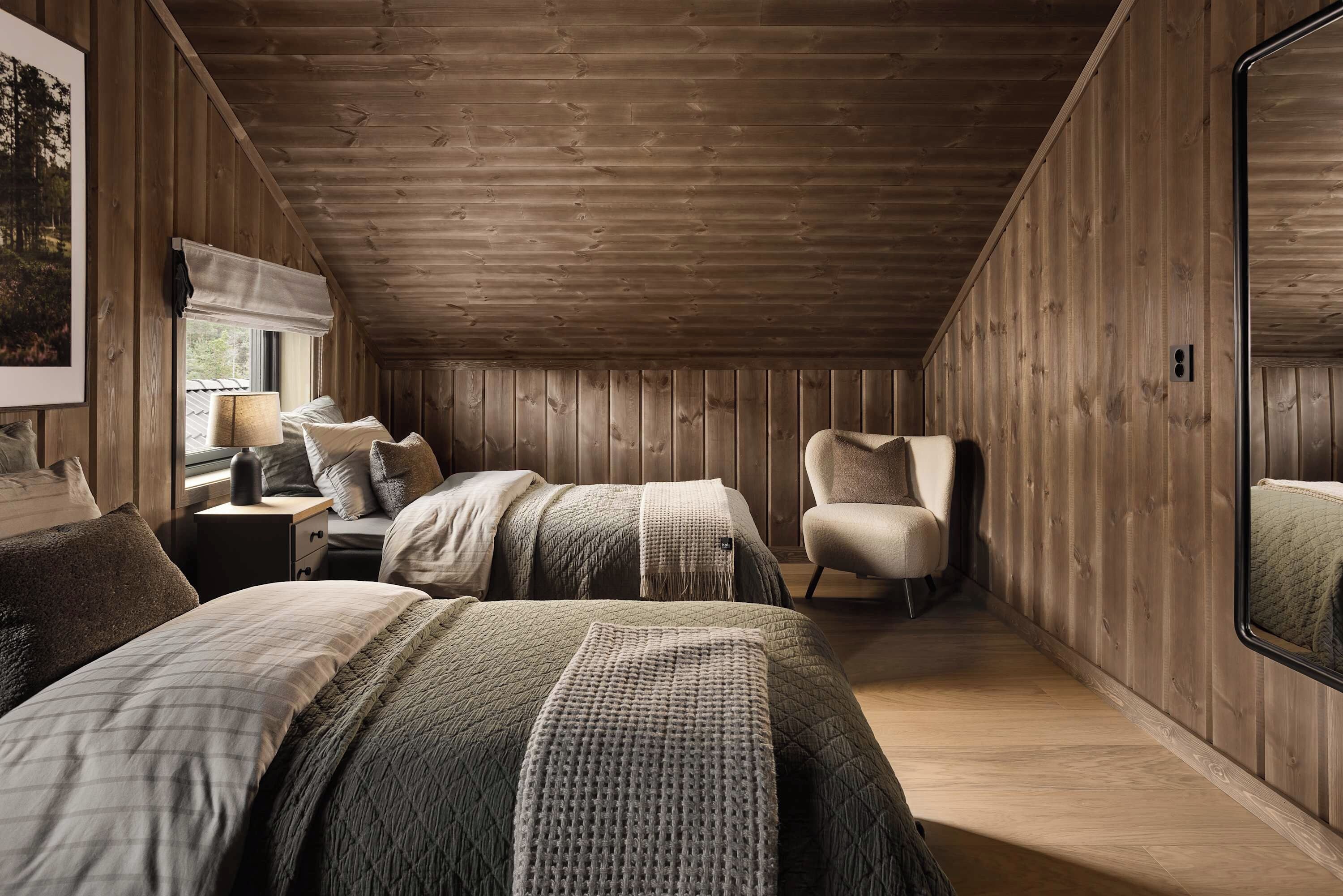 Een knus slaapkamer met houten wanden, een grote spiegel en een bed met veel kussens en een dekbed.