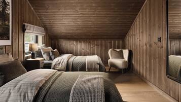 Une chambre confortable aux murs en bois, avec un grand miroir et un lit agrémenté de plusieurs oreillers et d’une couverture.