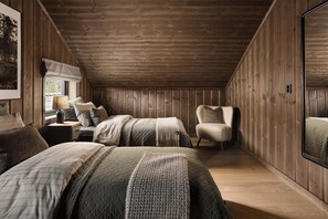 Un dormitorio acogedor con paredes de madera, un espejo grande y una cama con muchos almohadones y una manta.