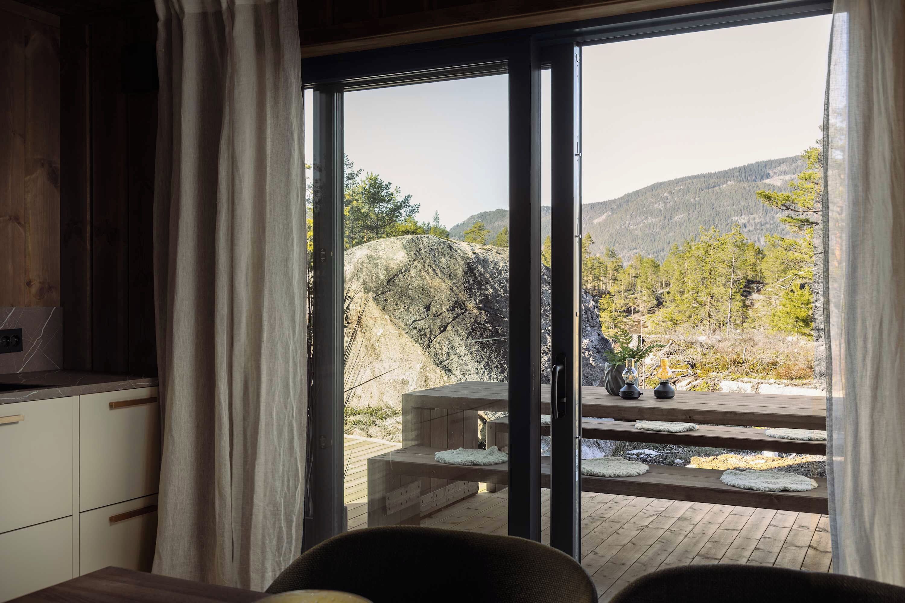 A room with a sliding glass door leading to an outdoor deck with a view of a mountainous landscape.