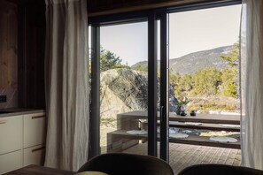 Habitación con puerta de vidrio corrediza que da a una terraza exterior con vistas a un paisaje montañoso.