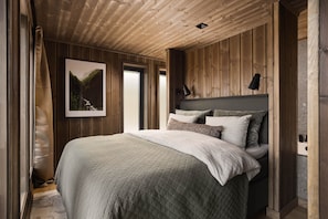 Une chambre avec un grand lit, des murs en bois, un tableau encadré et une table de chevet.