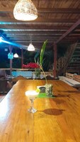 Una barra de madera con un cóctel en la barra, luces colgantes y una planta al fondo.