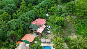 An aerial view of a tropical resort with a swimming pool, thatched-roof structures, and lush greenery. - Zelandia Eco Finca (Santa Marta)