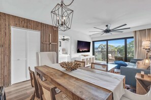 A modern dining area with a wooden table, chairs, and a ceiling fan. - I-452 - Remodeled, Luxury Condo with Lake Views (Naples)