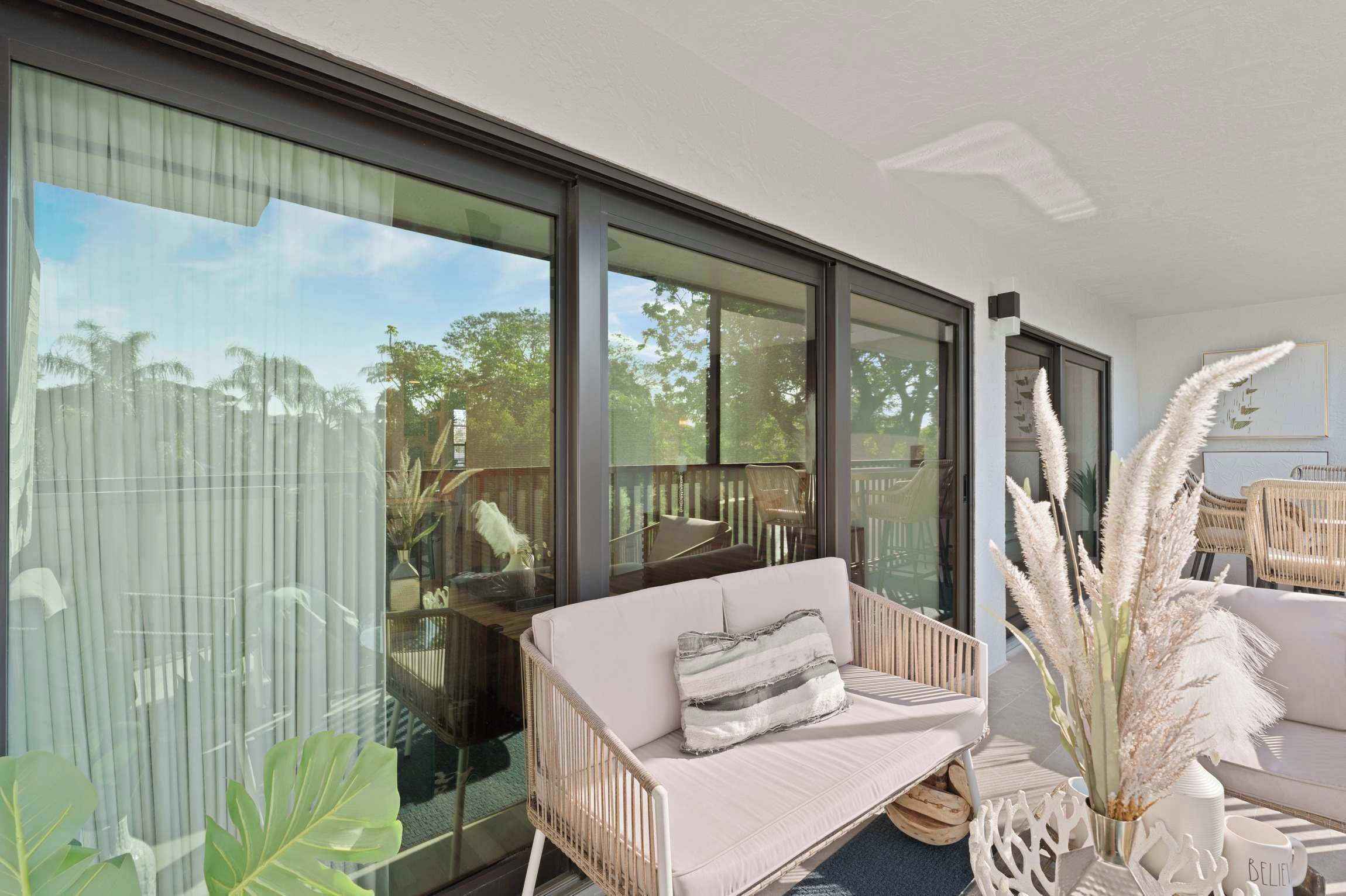 A modern living room with a sofa, large windows, and a view of the outdoors.