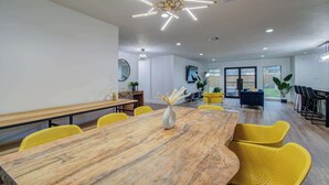 A modern conference room with a wooden table, yellow chairs, and a unique ceiling light fixture. - 5-BD Modern Central Getaway w Hot Tub - Mins to DT (Houston)