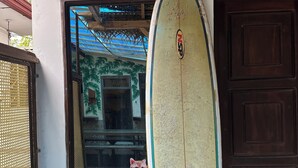 Ein Surfbrett, das an ein Gebäude gelehnt ist, mit einem Fenster und einer Tür.
