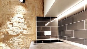A modern kitchen with a stone wall, black tiles, and a built-in oven.