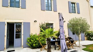 A building with a beige facade, blue shutters, and a gravel driveway. - La Belle de Jard - 8 people (Jard-sur-Mer)