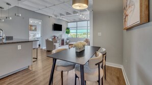 Una cocina moderna con una isla central, un comedor con mesa y sillas, y un ventanal que ofrece vistas al exterior.