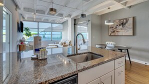 Una cocina moderna con encimeras de granito, lavavajillas integrado y un amplio ventanal con vistas a un balcón.