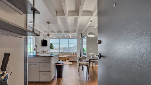 Una cocina moderna con una isla grande, un comedor con mesa y sillas, y una sala de estar con sofá y televisor.