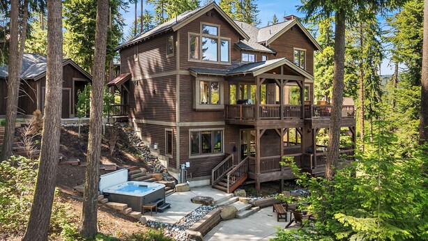 A two-story wooden cabin with a hot tub and outdoor seating area surrounded by trees. - Walk to the Winery & Chip onto the Par 3 Course! (Cle Elum)