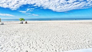 A sandy beach with footprints and a green umbrella. - ☀️Beachfront with Great Views and Amenities-Sea Oats #101☀️ (Redington Shores)