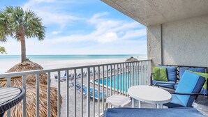 A balcony with a pool, lounge chairs, and a palm tree. - ☀️Beachfront with Great Views and Amenities-Sea Oats #101☀️ (Redington Shores)