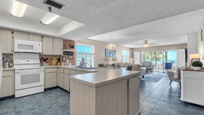A modern kitchen with a central island, built-in appliances, and a view to the living area. - ☀️Beachfront with Great Views and Amenities-Sea Oats #101☀️ (Redington Shores)