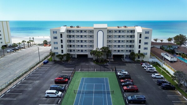 A multi-story hotel with a tennis court in the parking lot, a beach view, and a pool area. - ☀️Beachfront with Great Views and Amenities-Sea Oats #101☀️ (Redington Shores)