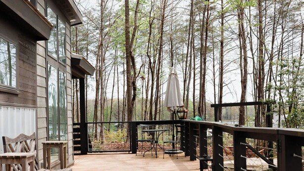 A wooden deck with benches and tables, surrounded by trees. - Be Still Tiny House on Monteagle Mountain  (Tracy City)