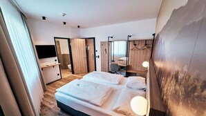 Een moderne hotelkamer met een groot bed, een bureau, een spiegel en een televisie.