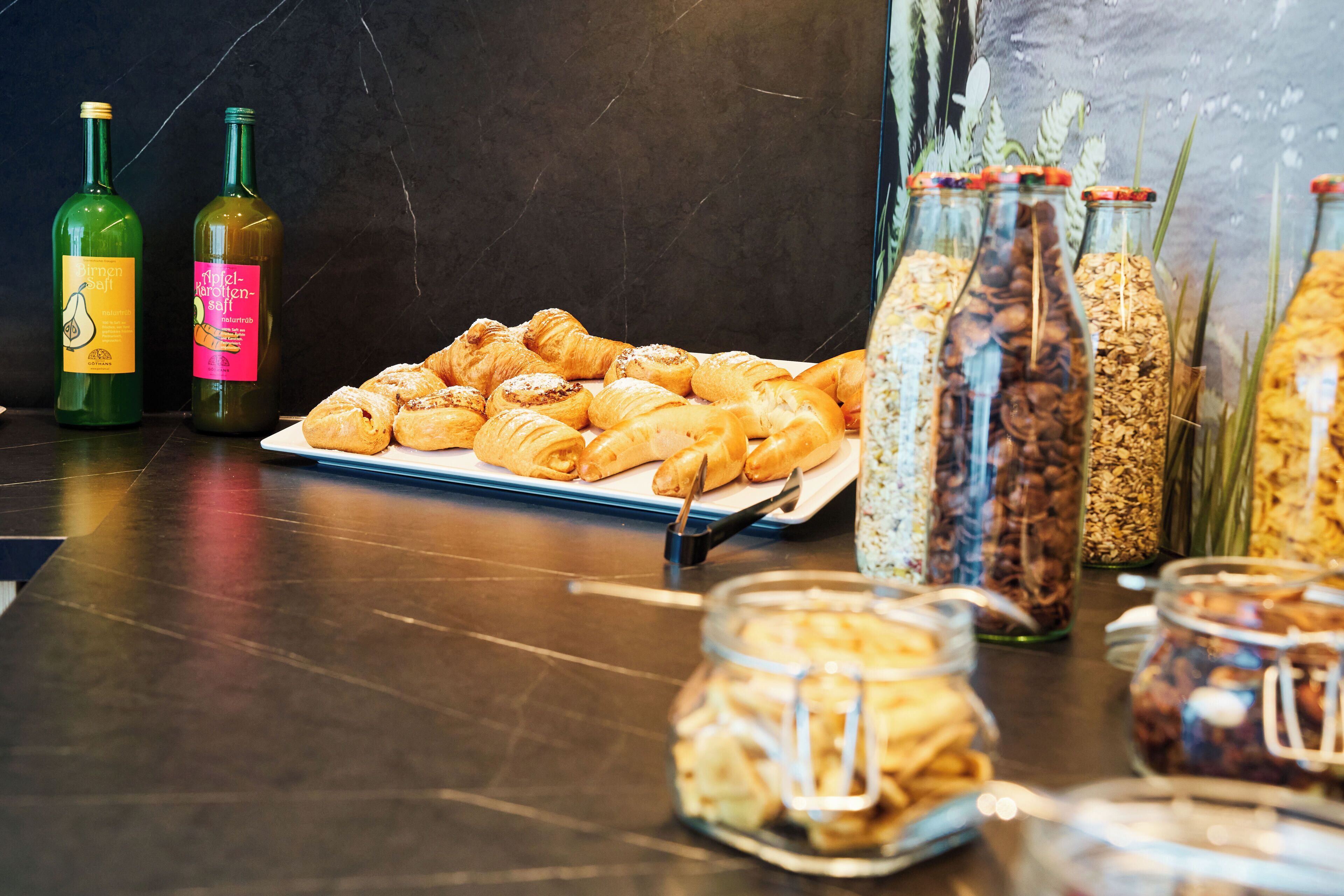 En buffetbord med croissanter, vinflasker og glas med pålæg.