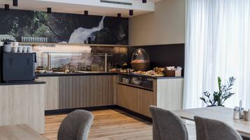 Una cocina moderna con un mural tipo cascada, armarios de madera y un comedor con sillas grises.