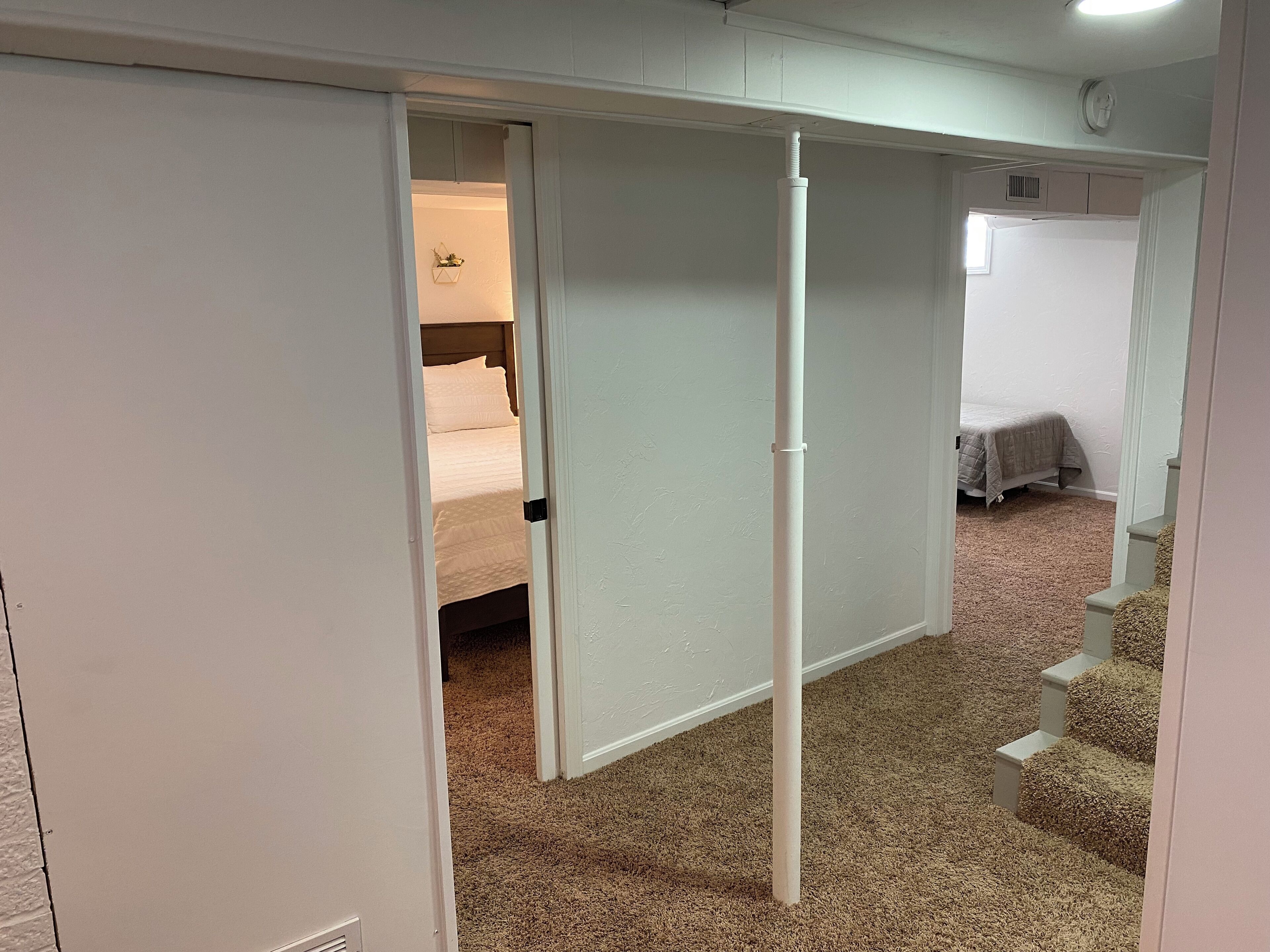 A room with a bed, a white door, and a carpeted floor.