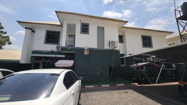 A two-story building with a flat roof and a large garage area. - VIMA HOTELS  (Abuja)
