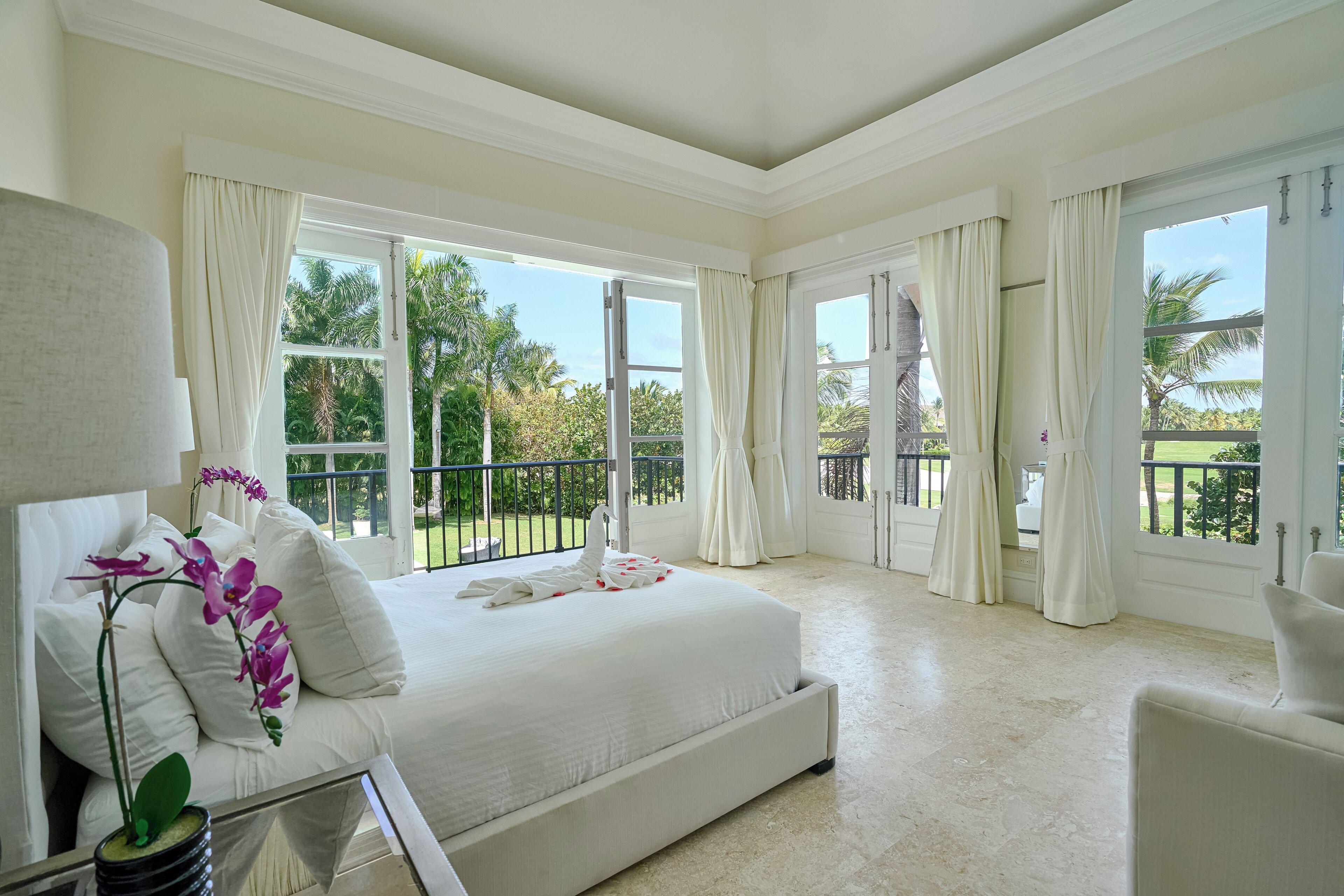 Quarto espaçoso com uma cama grande, área de estar e varanda com vista para o verde.