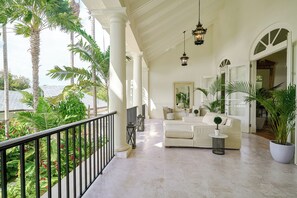 A spacious balcony with a white sofa, potted plants, and a view of the ocean. - Luxurious Ocean and Golf View Villa staffed with Private Chef, Butler and Maid! (Punta Cana)