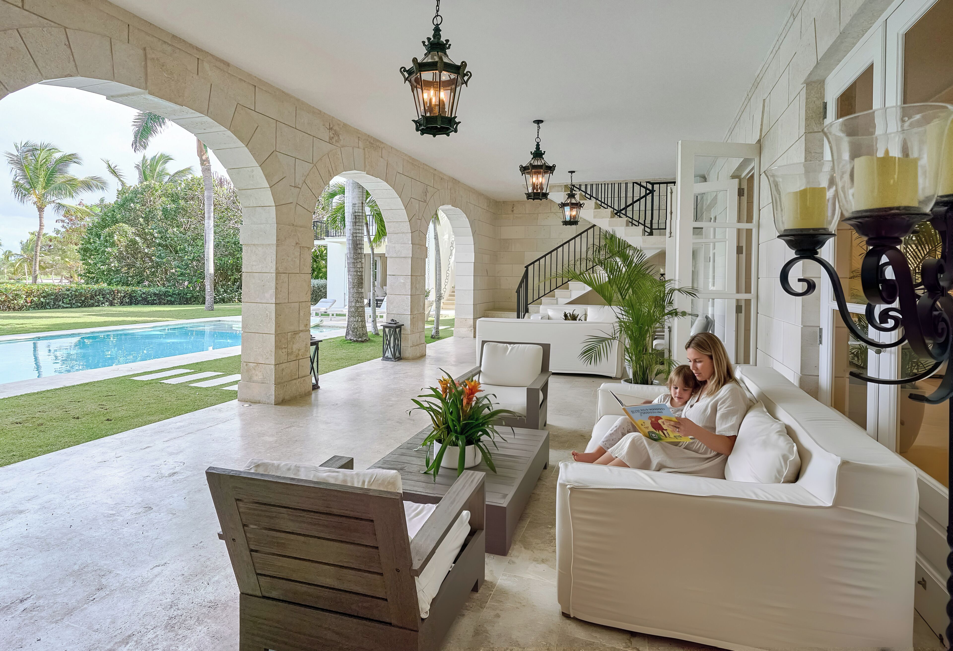Un espace extérieur abrité avec une piscine, des meubles blancs et un escalier.