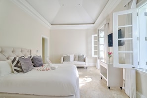 A bedroom with a large bed, a bedside table, a chair, and a wardrobe with a mirror.