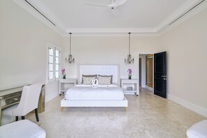 A spacious bedroom with a large bed, two bedside tables, a ceiling fan, and a black door. - Luxurious Ocean and Golf View Villa staffed with Private Chef, Butler and Maid! (Punta Cana)