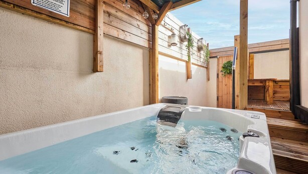 Lämminvesiallas, jonka ympärillä on puinen terassi ja jonka yläpuolella on pergola.