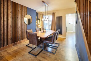 Un comedor con mesa de madera, sillas de cuero e iluminación colgante.