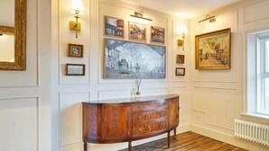 A room with a wooden cabinet, wall-mounted picture frames, and a radiator. - Host & Stay | The Rooftop Gallery (Jesmond)