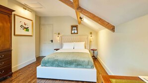 A bedroom with a large bed, wooden beams, a dresser, and framed artwork on the wall. - Host & Stay | The Rooftop Gallery (Jesmond)