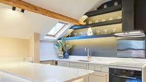 A modern kitchen with a large island, built-in oven, and a skylight. - Host & Stay | The Rooftop Gallery (Jesmond)