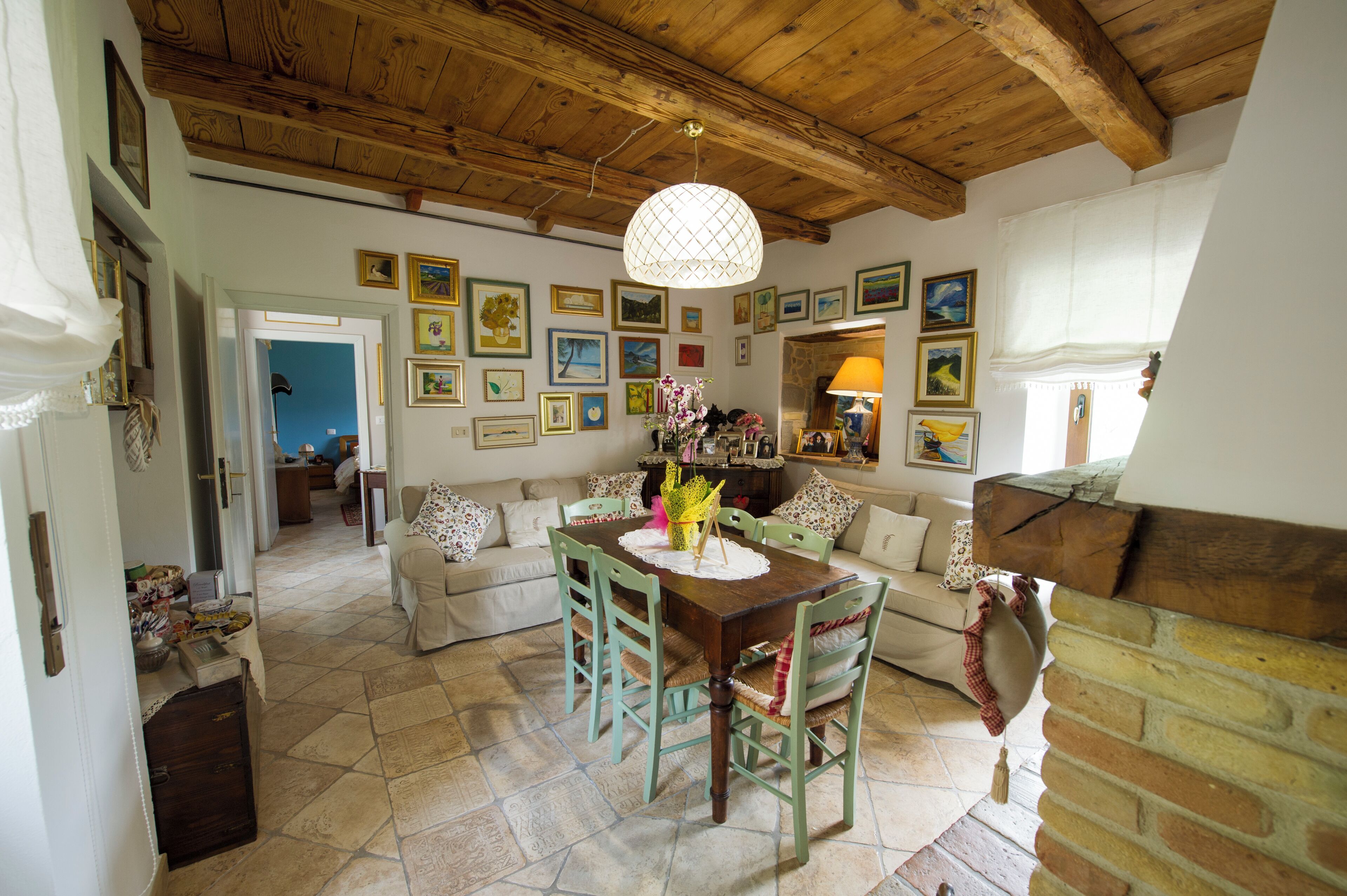 A dining area with a wooden table and chairs, surrounded by a brick fireplace and a wall adorned with framed pictures.