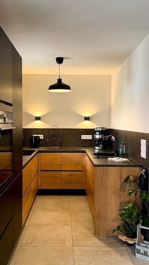 A modern kitchen with wooden cabinets, a central island, and pendant lighting. - Breathing space-Spreewald (Vetschau/Spreewald)