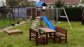 A backyard with a wooden play structure, a blue slide, and a picnic table with benches. - Breathing space-Spreewald (Vetschau/Spreewald)