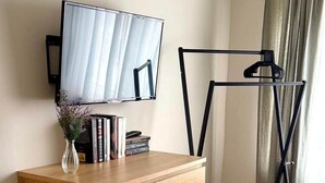 A room with a wooden dresser, a television mounted on the wall, and a black metal drying rack. - Breathing space-Spreewald (Vetschau/Spreewald)