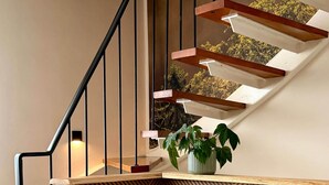 A staircase with wooden steps and black railings, a potted plant on the landing, and a patterned wall. - Breathing space-Spreewald (Vetschau/Spreewald)