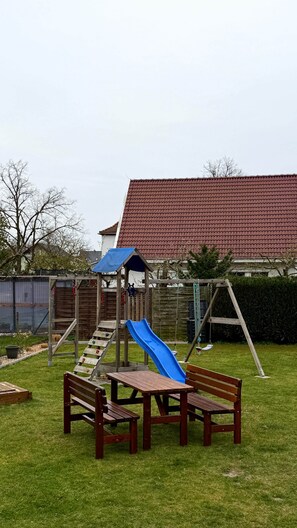 A playground with a slide, swings, and picnic tables in a grassy yard. - Breathing space-Spreewald (Vetschau/Spreewald)