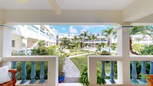 A hotel balcony with a view of a pool, palm trees, and other buildings. - ☀️⛱️Beachside by IRE Vacations - 3 bedroom Condo on Simpson Bay Beach 🌴 (Simpson Bay)