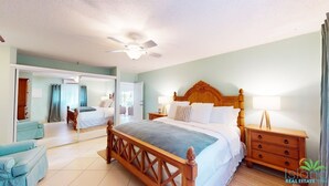 A spacious bedroom with a large bed, a wooden headboard, a nightstand, and a ceiling fan. - ☀️⛱️Beachside by IRE Vacations - 3 bedroom Condo on Simpson Bay Beach 🌴 (Simpson Bay)