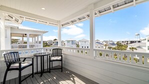 A covered porch with a table and chairs, overlooking a residential area. - 30A House with Pool and Bunk Rooms (Seacrest Beach)