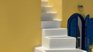 A set of white stairs leading up to a blue door, surrounded by yellow walls. - Ilivatos - Elegant Villa on the Caldera's Edge (Oia)